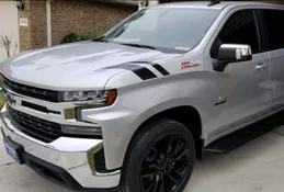 A silver truck with black stripes on the hood.